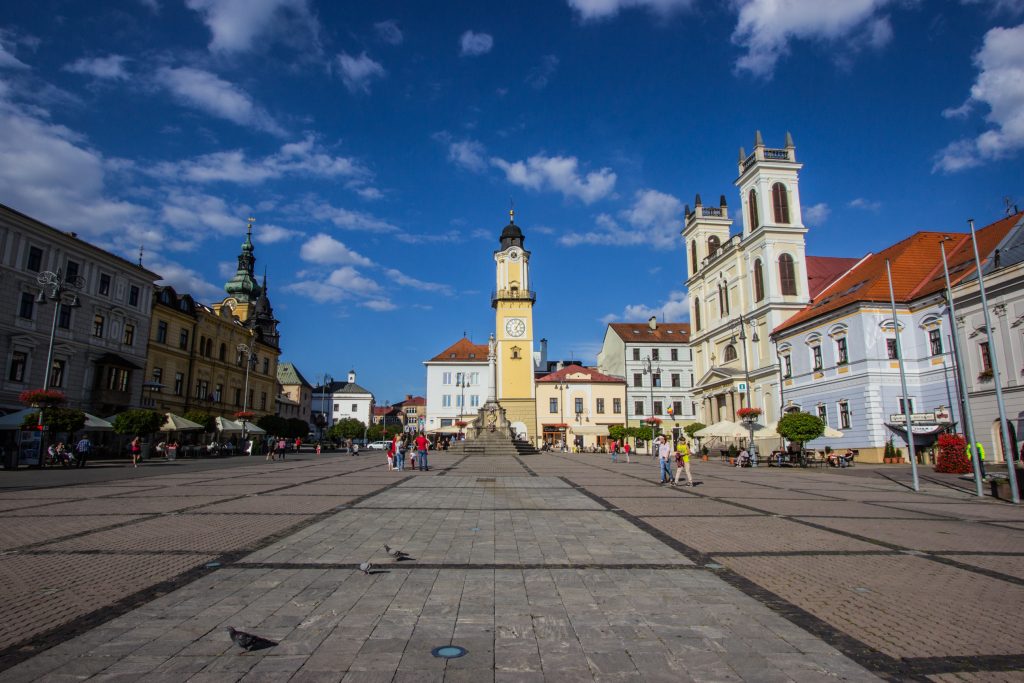 Górna część Placu Słowackiego Powstania Narodowego. W centrum wieża zegarowa, po prawej Katedra św. Franciszka Ksawerego w Bańskiej Bystrzycy.